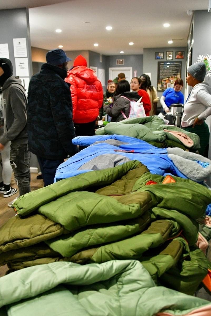 A group of people standing around sleeping bags.