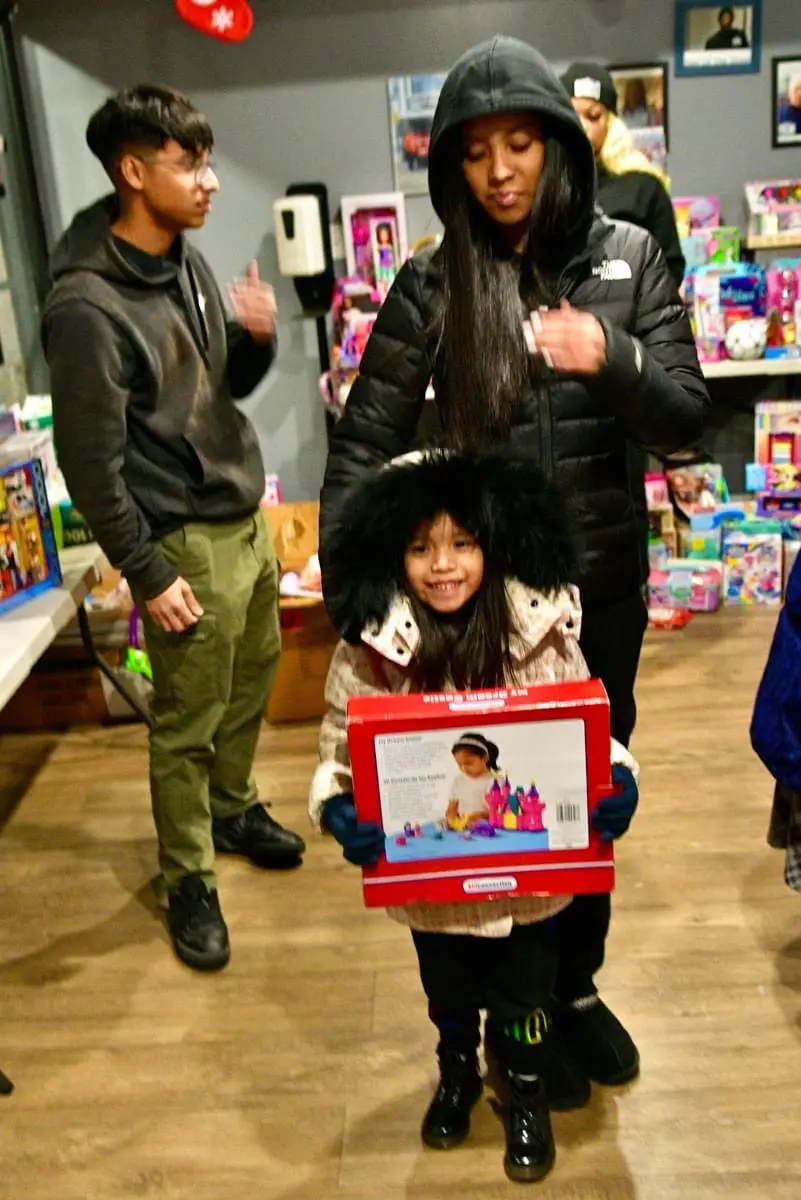 A little girl holding onto a box in the middle of a store.