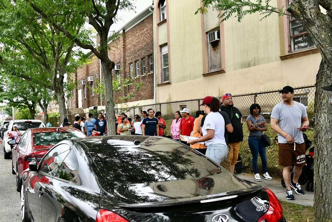 A crowd of people standing around a car.