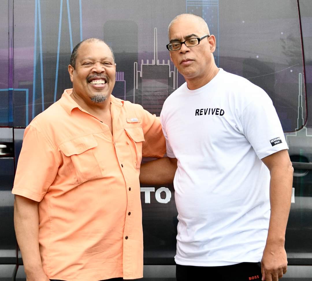 Two men standing next to each other in front of a building.