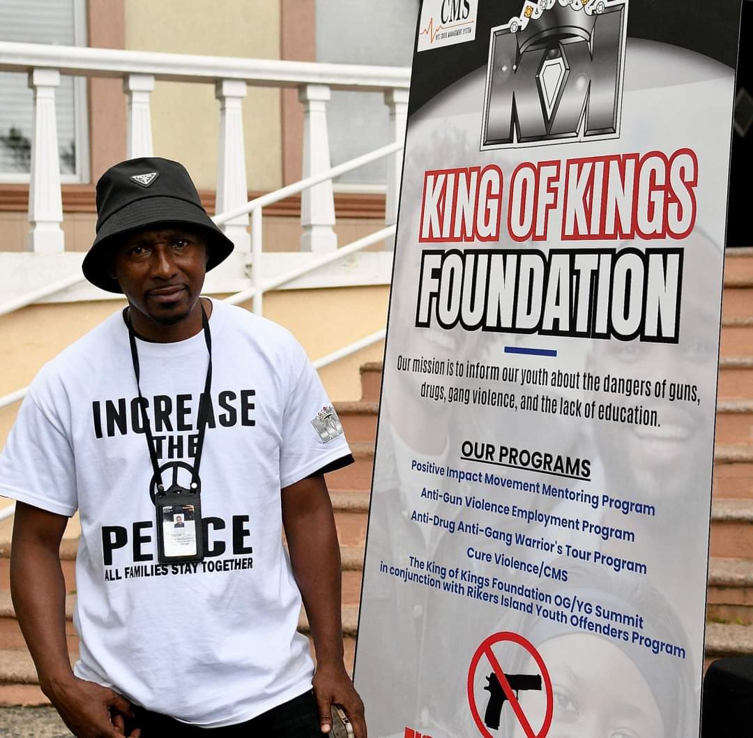 A man standing next to a sign that says " increase the peace ".