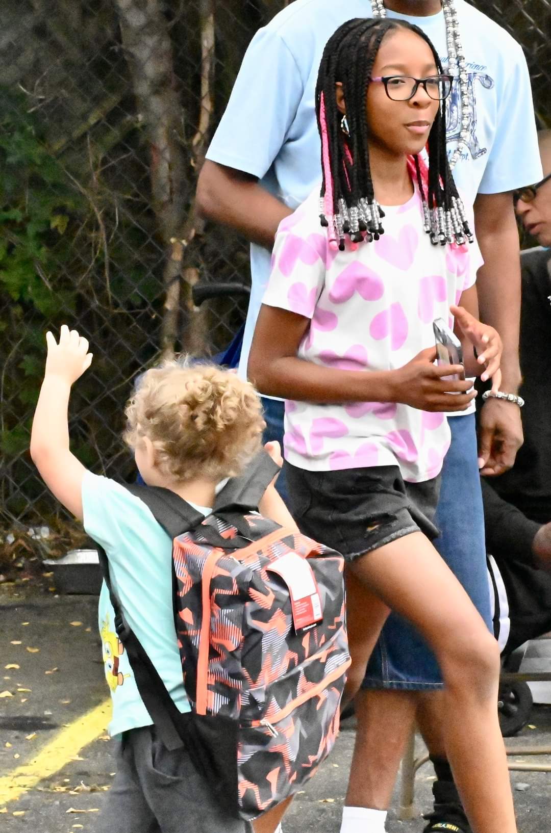 A boy and girl with backpacks on the sidewalk.