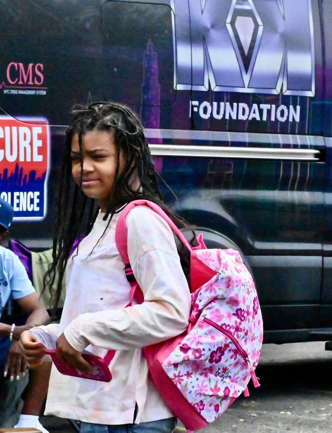 A girl with dreadlocks walking down the street.