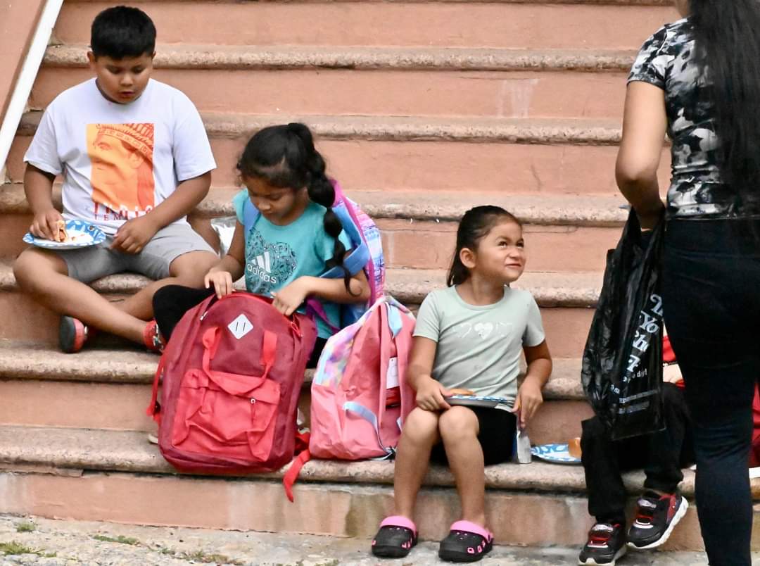 A group of children sitting on steps with backpacks.