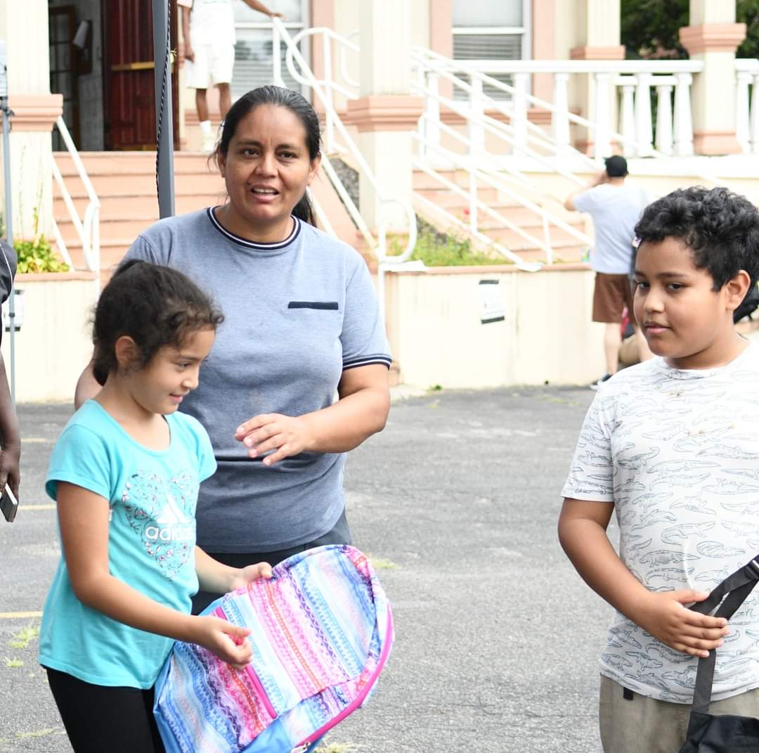 A woman and two children are standing on the sidewalk.