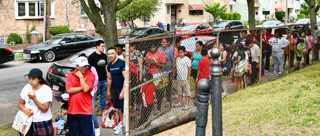 A group of people standing around a fence.