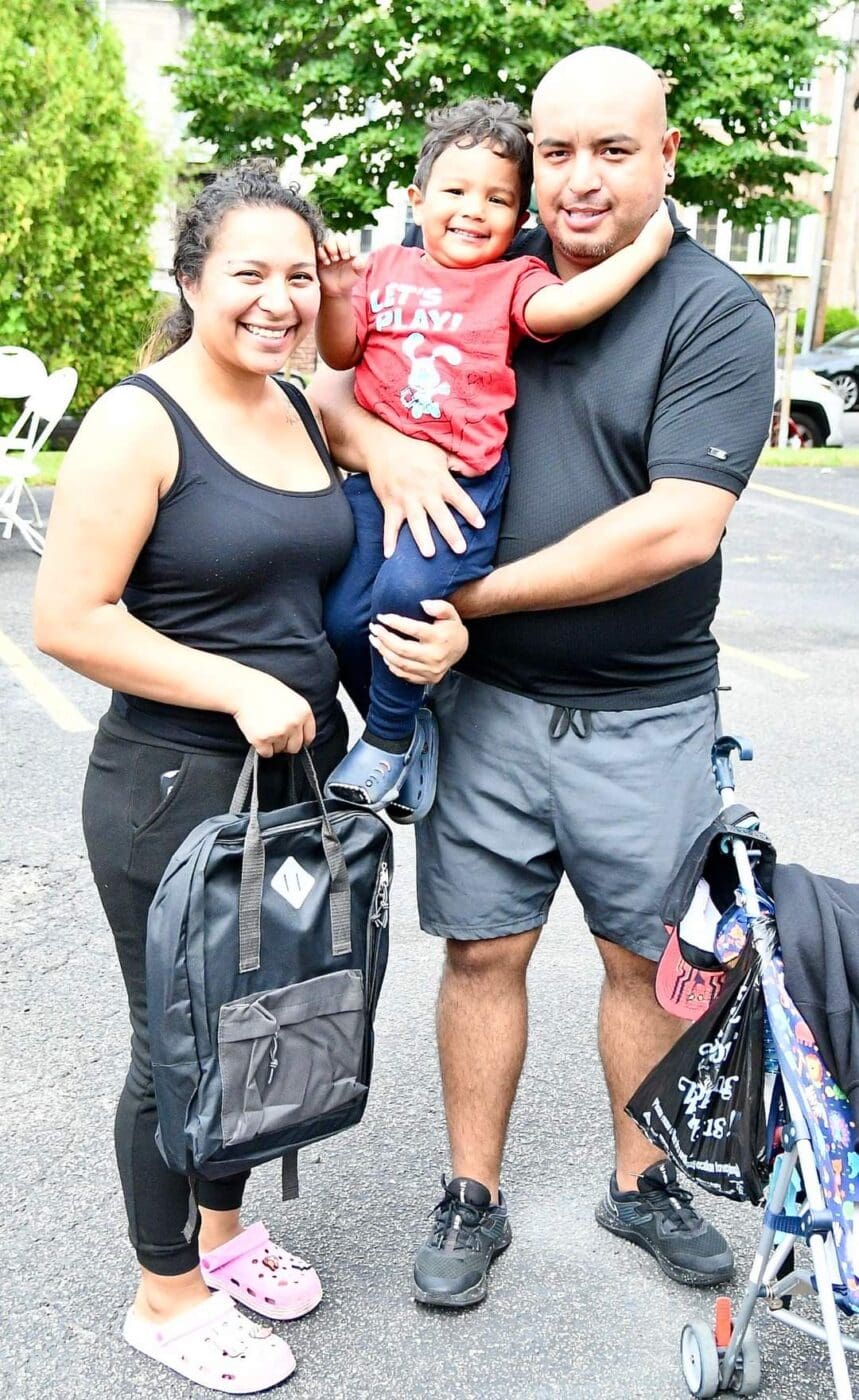 A man and woman holding a child in front of luggage.